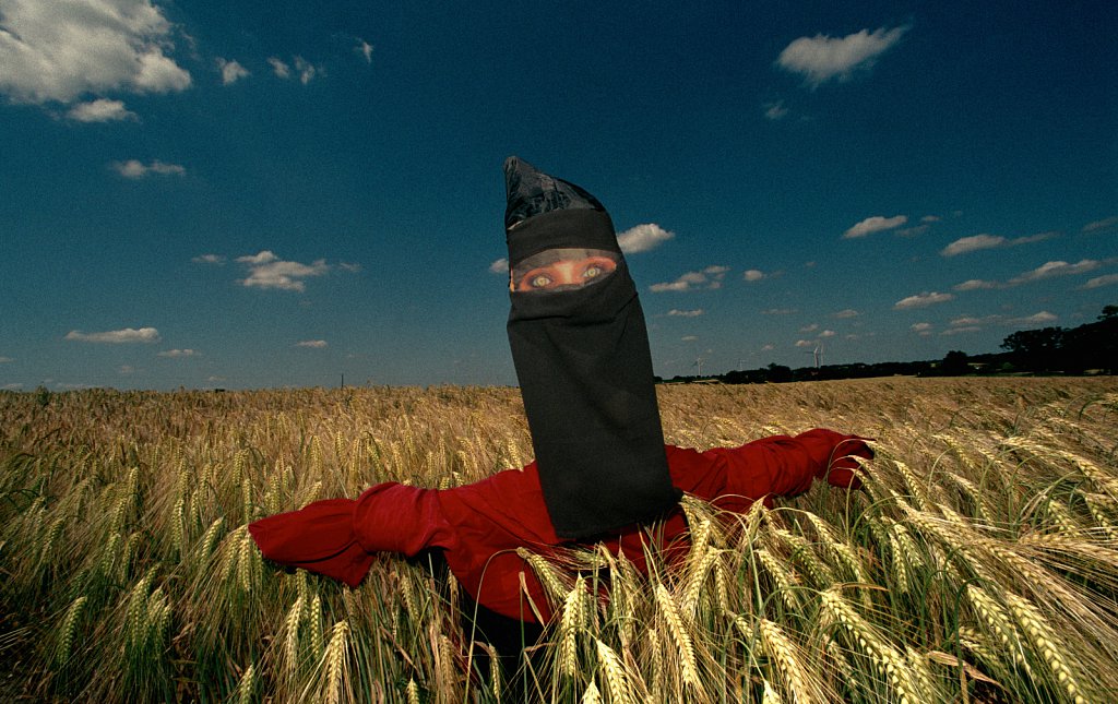 A scarecrow with a niqab in a field of wheat